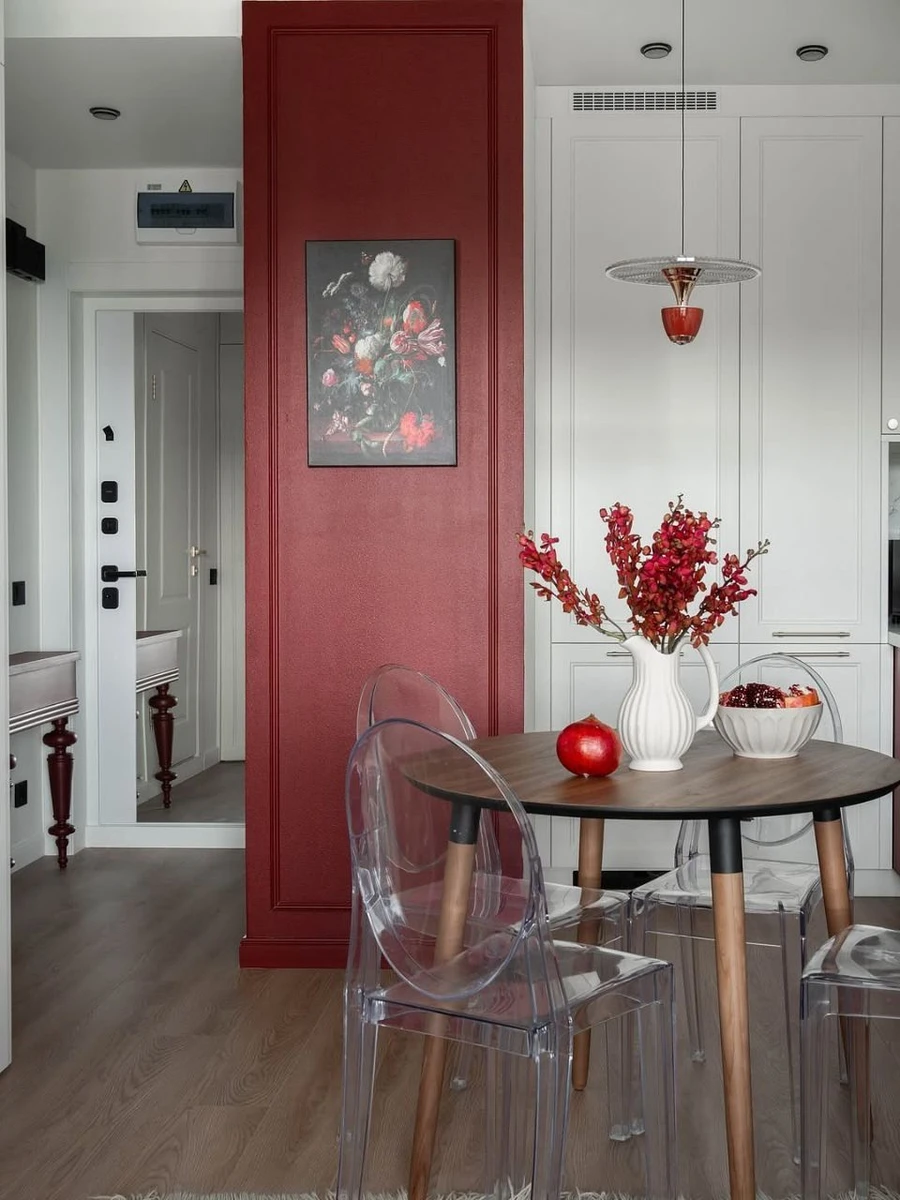 Обеденная зона с прозрачными стульями и красной стеной