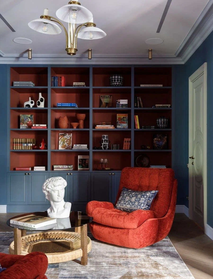 Просторная гостиная с синим стеллажом и красным креслом