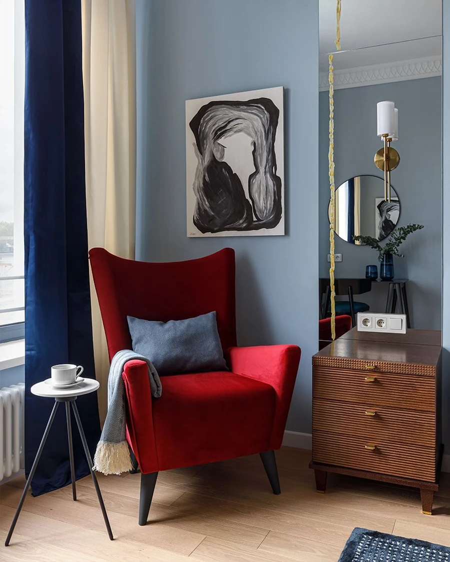 Спальня с голубыми стенами и красным креслом
